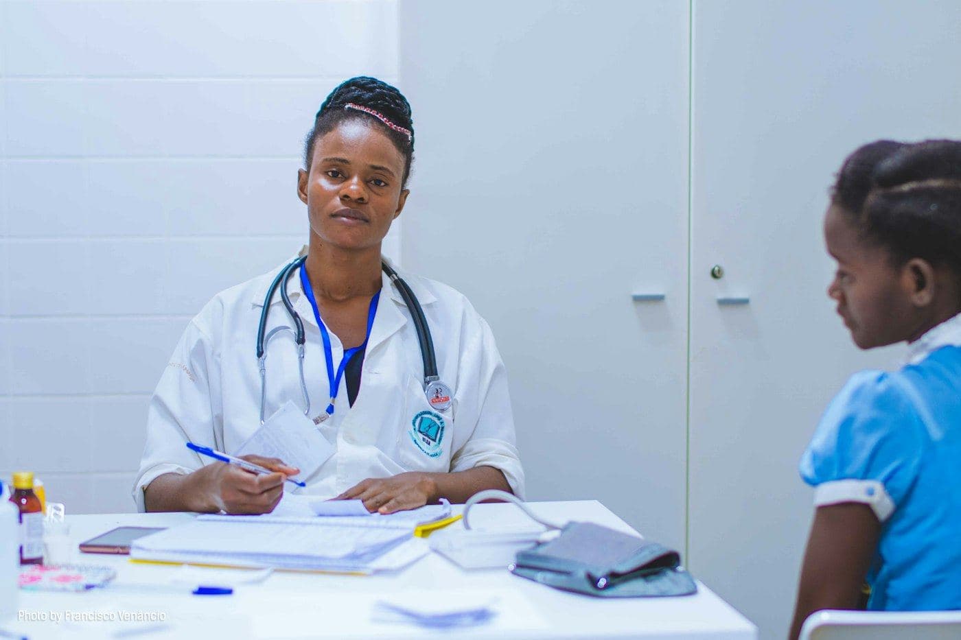 A doctor writing notes at a desk in a clinic.