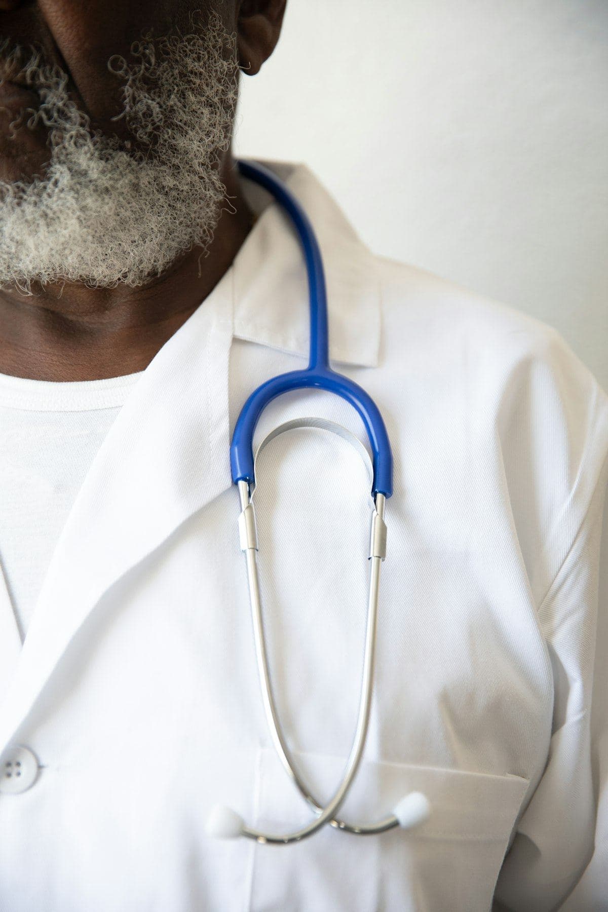 A clinician in a white coat, a stethoscope around their neck.