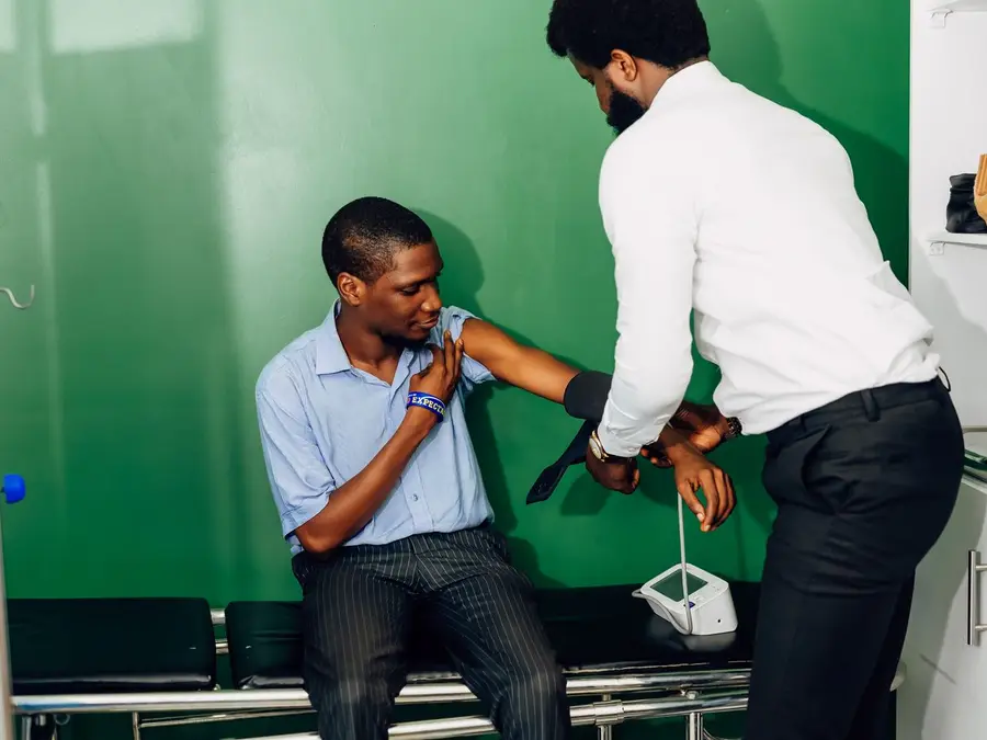 A doctor fitting a blood pressure cuff on a patient's arm